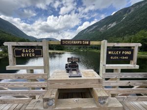 Wooden bridge at Dickerman’s Dam with signs for the Saco River and Willey Pond
