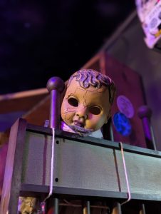Creepy doll head on top of a gate in The Last Bookstore in Los Angeles. A cracked doll head without eyes in a dark room with a bookshelf in the background.