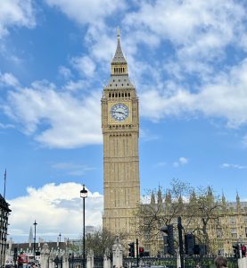 A close-up of Big Ben and the Houses of Parliament against a partly cloudy blue sky in London, UK.