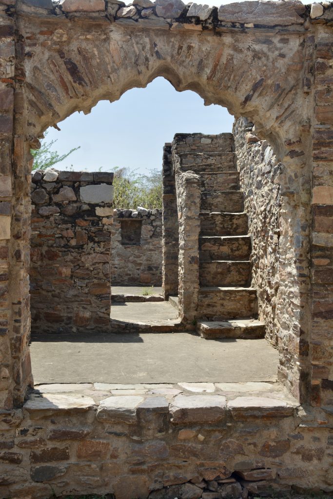 Small arched window in Bhangarh Fort’s ancient walls framing a view of its interior.