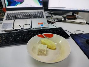 A bowl with two pieces of food is placed on a desk.