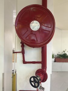 A fire hose reel, mounted on a white wall.