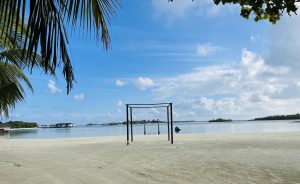 A tranquil beach scene featuring a sandy shoreline and calm blue waters under a partly cloudy sky
