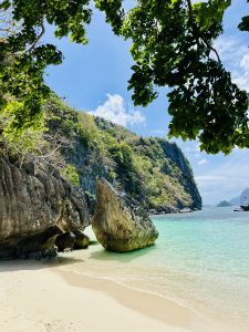 A serene beach scene featuring soft, beige sand gently meeting clear, turquoise water.