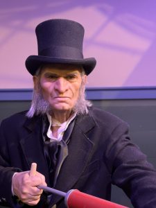 An animatronic Ebenezer Scrooge holding a bug smoker.
