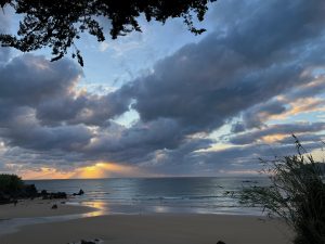 A picture of a scattered cloudy colorful sunrise on the beach with few sea waves and in its edge. #SummerPhotoContest