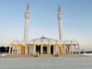 A modern mosque with two tall minarets flanking a grand entrance.