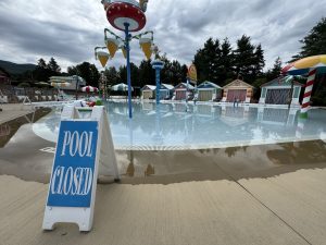 A splash pool surrounded by colorful cabanas and water features at Santa’s Village in Jefferson, New Hampshire. There’s a sign in the foreground that reads “pool closed.” 