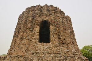 Close-up of the Alai Minar in Delhi, showing the detailed stonework and arched opening of this incomplete historic tower.
