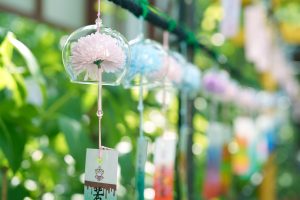 Colorful glass wind chimes, each with flowers inside, hanging and swaying gently in the summer sunlight—capturing the essence of Japanese culture, a cool summer breeze, and seasonal decoration
