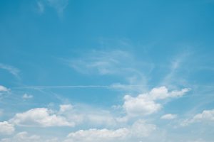 A bright blue sky dotted with soft white clouds, evoking freedom, nature, summer, and calm.
