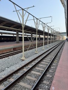 A view of a railway station with visible train tracks and concrete platforms. 