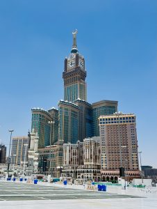 The magnificent Abraj Al-Bait clock tower in Mecca, Saudi Arabia, standing tall against a brilliant blue sky.
