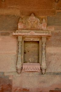 An ornate red sandstone niche with intricate carvings, showcasing Mughal architectural detail. Captured at Fatehpur Sikri, Uttar Pradesh.