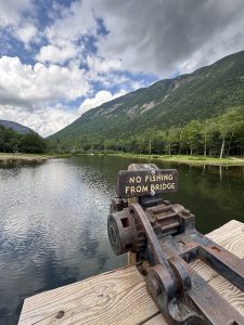 A sign that says “no fishing from bridge” on a metal gear attached to a wooden bridge over Dickerman’s Dam, which separates the Saco River and Wiley Pond in Hart’s Location, New Hampshire. 