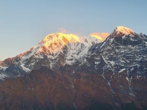 A mountain range at sunrise, with the morning sun illuminating the snow-covered peaks