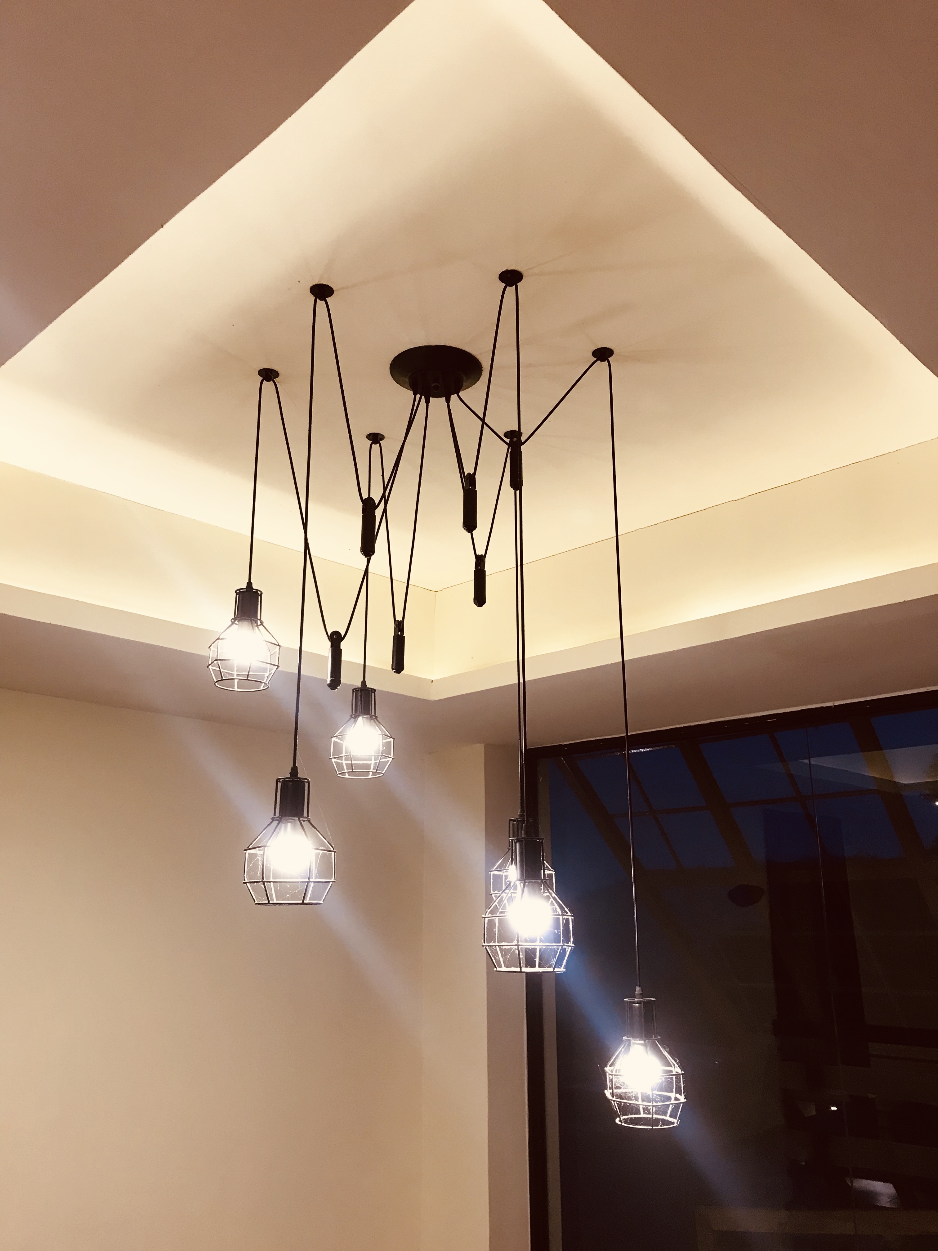 A spider-like light fixture with six exposed bulbs in cages hangs from a white ceiling.