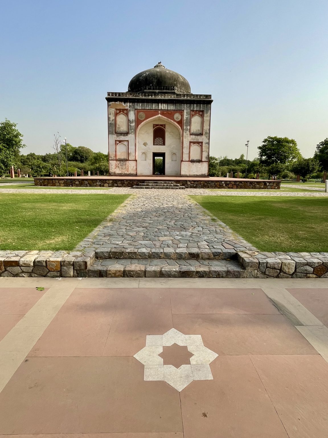 Mughal-era tomb set in landscaped gardens of Sunder Nursery aka Azim Bagh in Delhi, featuring symmetrical architecture with a black dome and red sandstone accents.