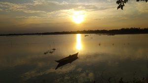 A serene sunset over a calm body of water, with the sun casting a golden reflection on the surface.