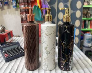 Three decorative pump bottles are displayed on a striped table surface.