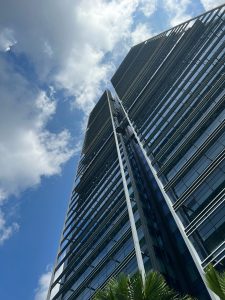 A low-angle view of two modern skyscrapers with glass facades, reaching up into a blue sky with white clouds.