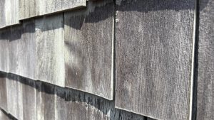 A closeup of weathered old wooden shingles used as siding on a building.