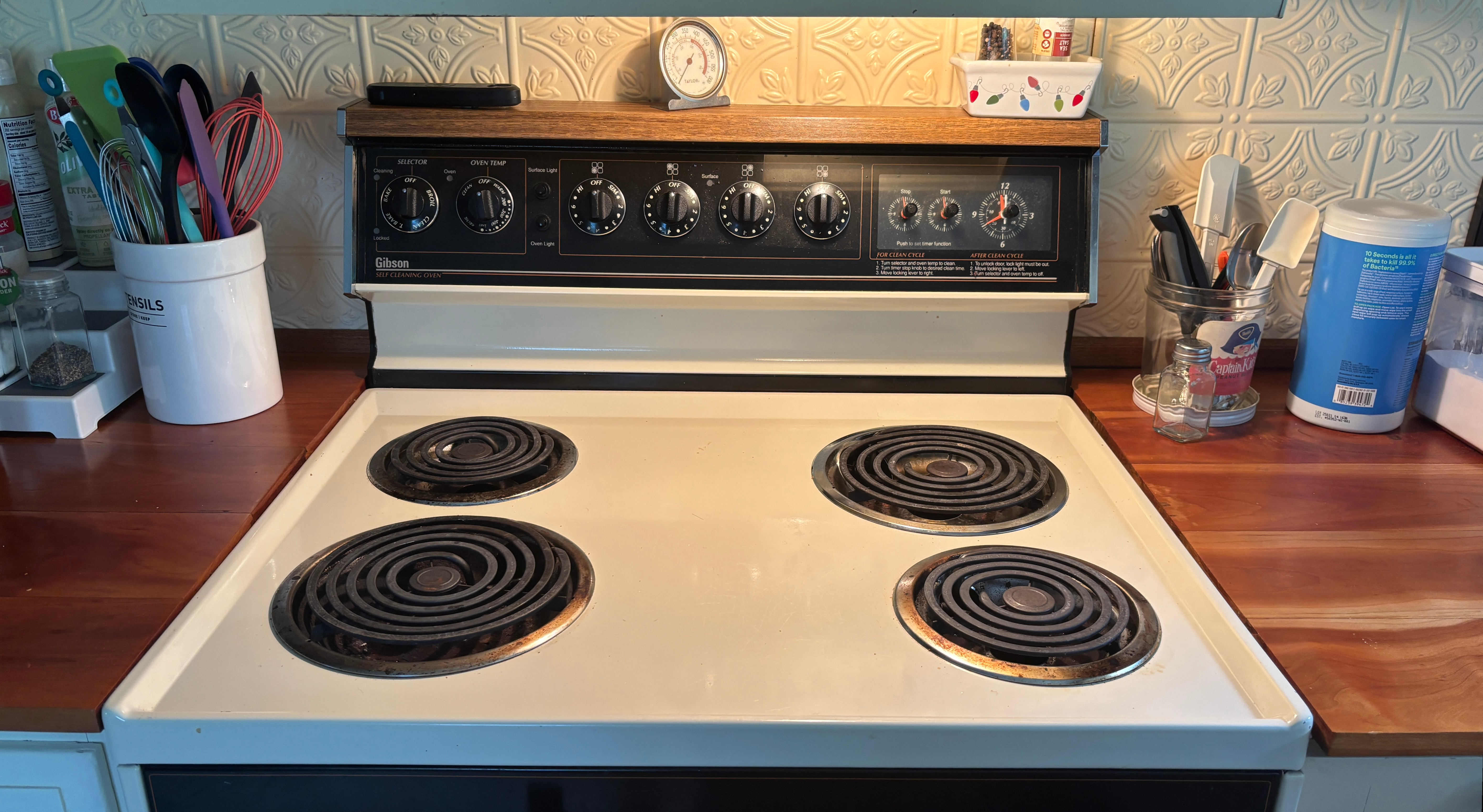 A stovetop in a kitchen, cooking tools on a counter on either side.