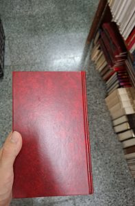 The back cover of a red hardcover book held by a hand.
