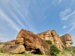 Sunlit red sandstone cliffs of Badami, Karnataka, with layered textures revealing the passage of time.