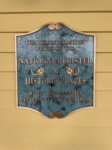 A green plaque with gold lettering on a yellow wall at the Mountain View Grand Resort & Spa in Whitefield, New Hampshire. It reads “This place has been placed on the national register of historic places by the United States Department of the Interior.

