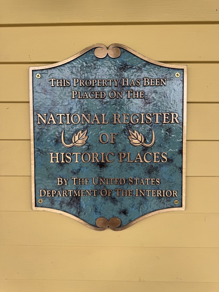 A green plaque with gold lettering on a yellow wall at the Mountain View Grand Resort & Spa in Whitefield, New Hampshire. It reads “This place has been placed on the national register of historic places by the United States Department of the Interior.