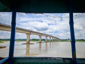A view of a wide river with a concrete bridge spanning across it.