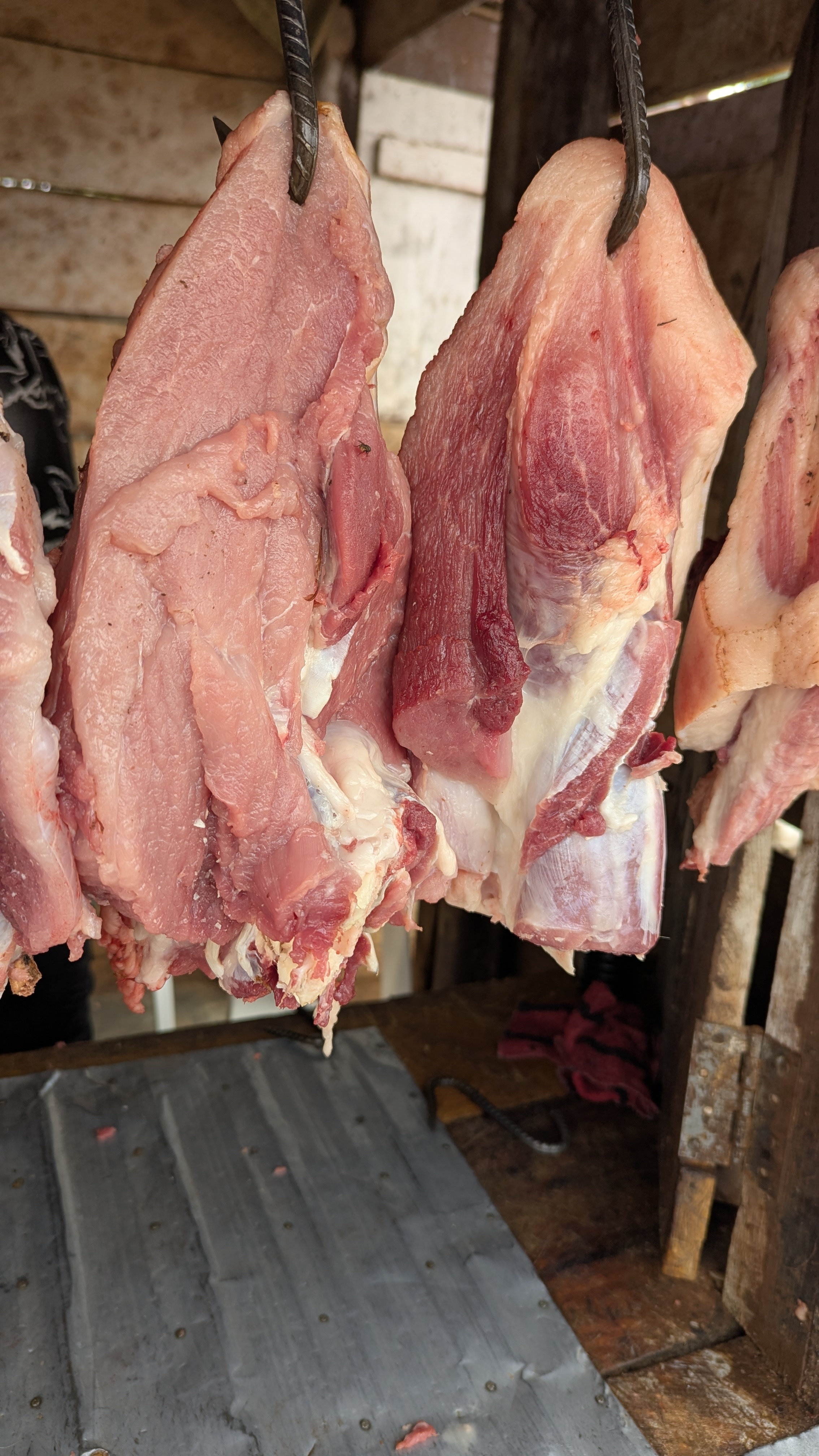 A display or large cuts of meat hanging on hooks at the butchery