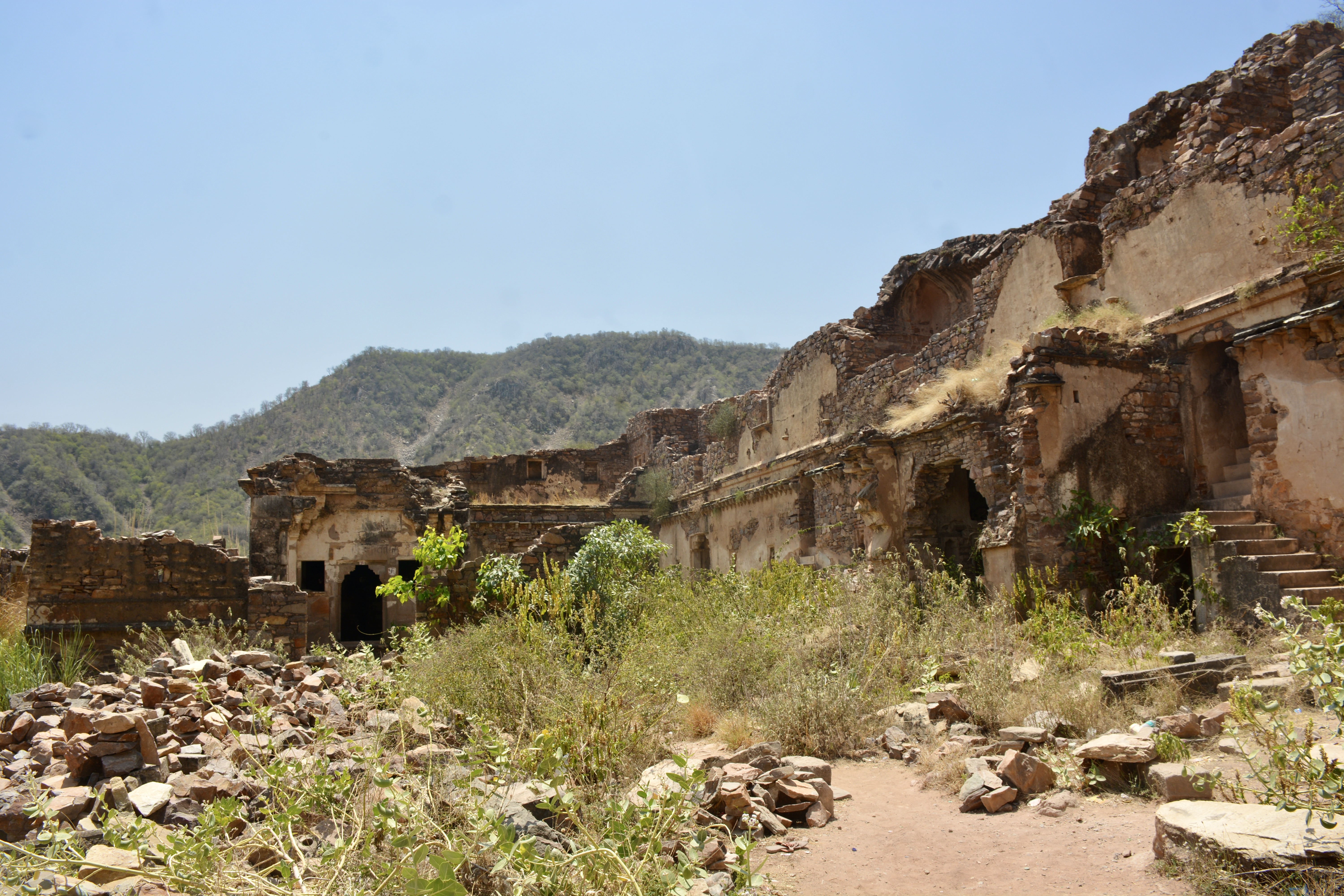 Partially collapsed walls of Bhangarh Fort stand against the surrounding hills, their textures telling centuries of history.