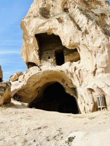 A close-up of a large cave entrance carved into a weathered rock formation at Cappadocia, Turkey.
