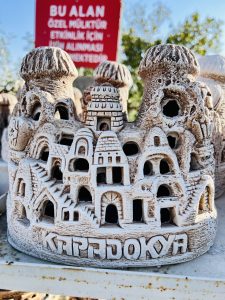 A low-angle close-up shot of a decorative, light-colored ceramic piece designed to look like the fairy chimneys and cave dwellings of Cappadocia, Turkey.