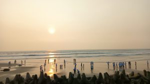 

A beach scene during sunset with people walking along the shoreline. 