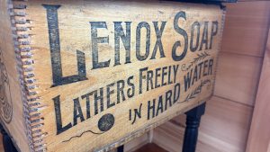 An antique wooden box with an old fashioned advertisement on the side.