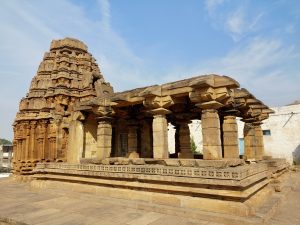 An ancient stone temple of Badami stands gracefully, its ornate pillars and carvings echoing the craftsmanship of a glorious past.