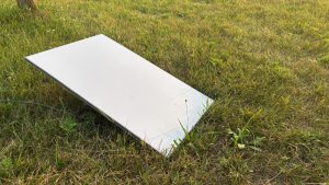 A rectangular satellite receiver on the grass, pointed at the sky.