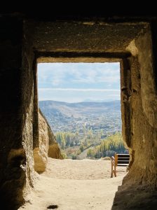 A view of the valley and a distant town, seen from inside a cave through a rectangular opening, at Cappadocia, Turkey.