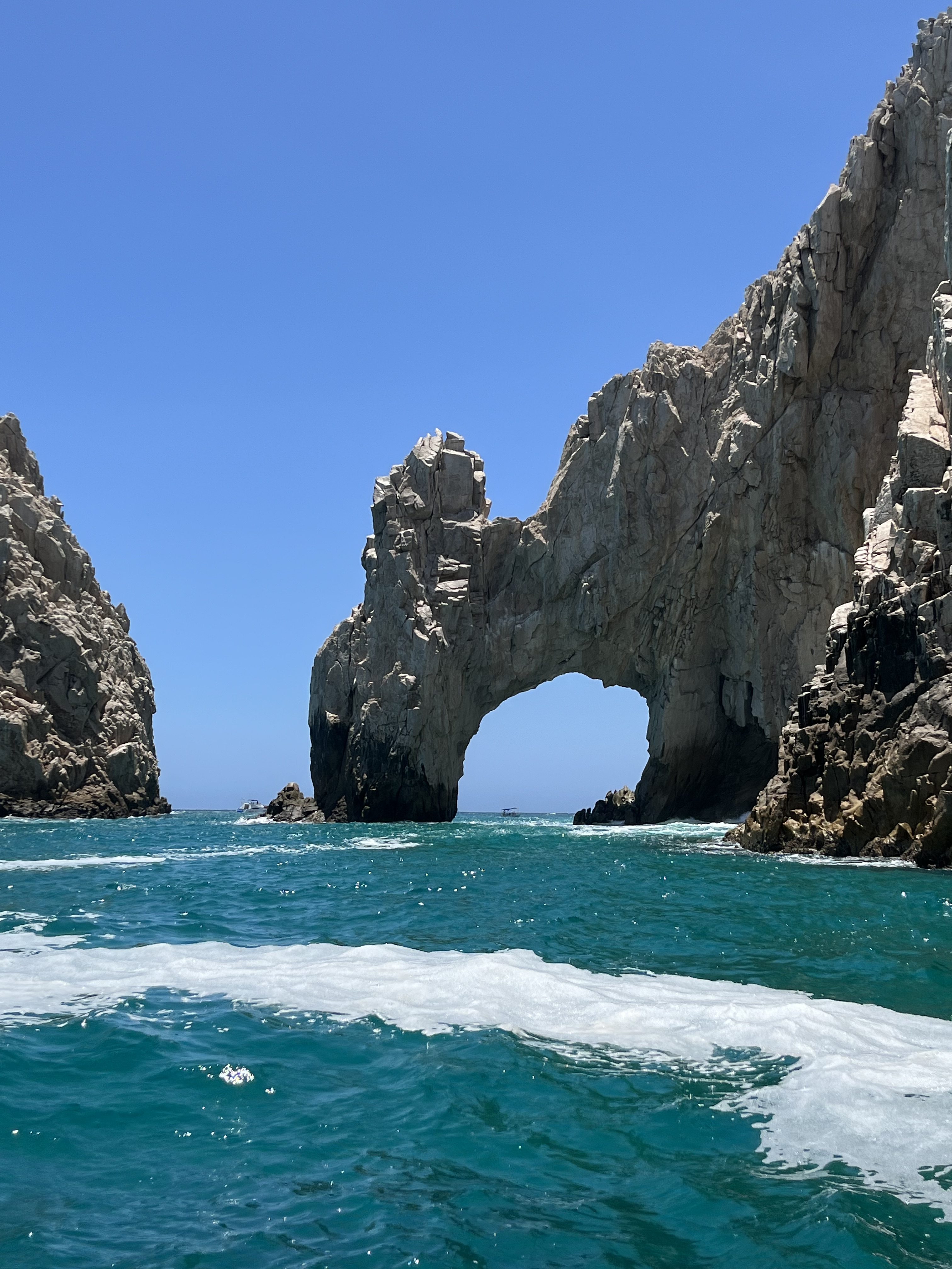 A stunning view featuring the vibrant blue sky, turquoise sea, and the iconic Arch of Los Cabos in the background. This breathtaking coastal landscape perfectly captures the natural beauty and tranquility of the region.