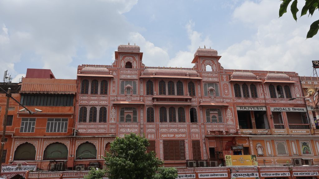 Navkar Mahal Pink City Jaipur. The structure features several windows with decorative grilles and an elevated roof adorned with small domes.