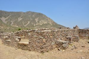 The weathered fortress wall of Bhangarh Fort, Alwar, Rajasthan, is set against the rugged landscape of the Aravalli Hills. 