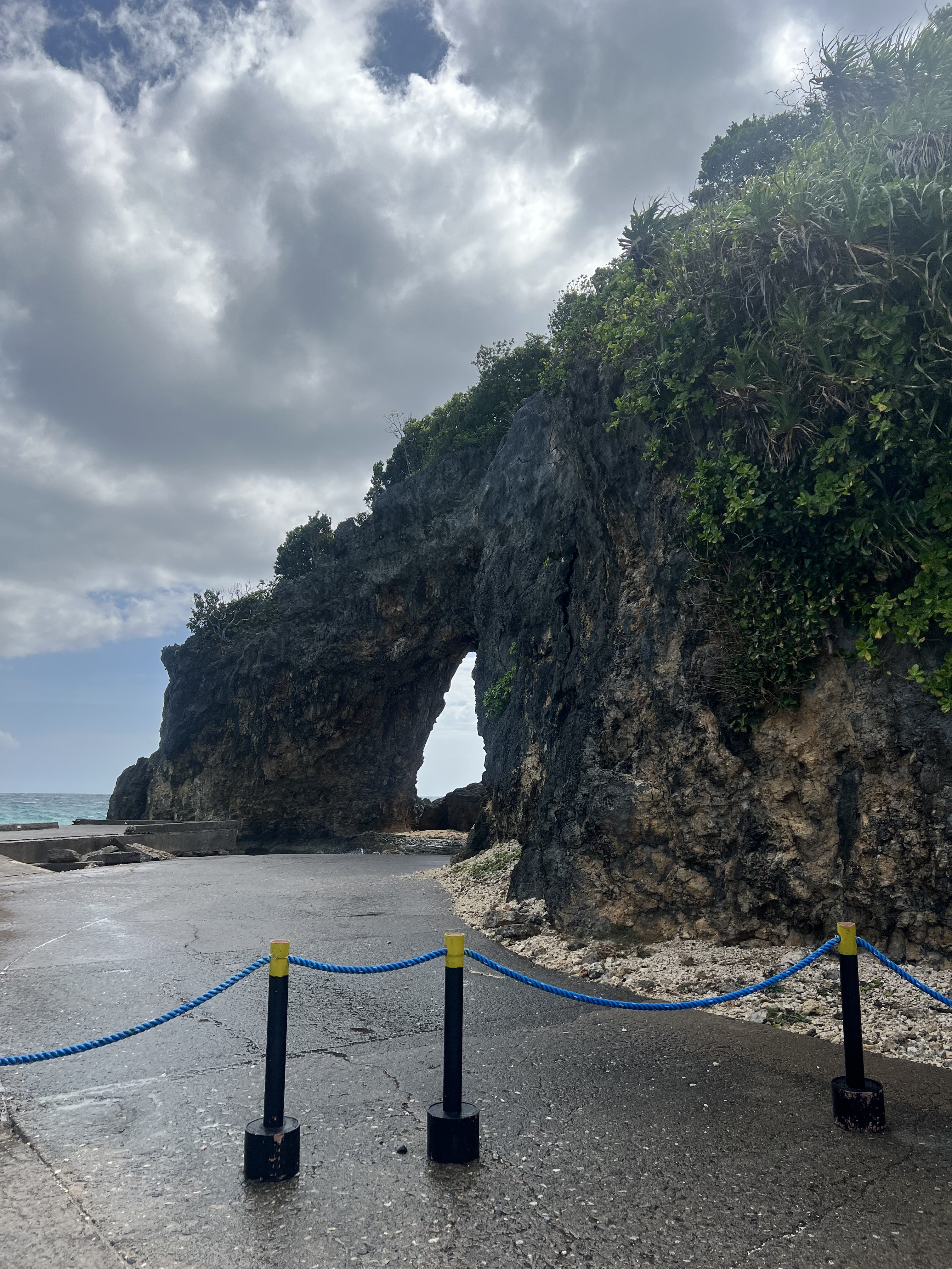 A rocky arch by the sea in Boracay, with wet pavement and a blue rope barrier in the foreground