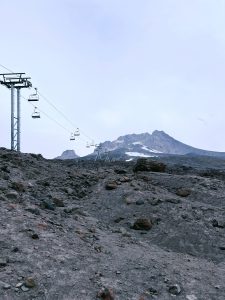 Ski lifts going towards a mountain with volcanic rock ground visible at the bottom