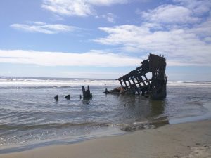 Shipwreck of the Peter Iredale in Hammond, Oregon. The rusted skeleton of an old ship protrude from the beach.