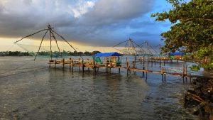 Chinese fishing nets at Fort Kochi, Kerala, India, at dusk or dawn, with the nets silhouetted against a calm body of water and a colorful sky.

#SummerPhotoContest