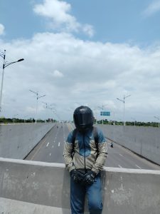 A person wearing a full-face motorcycle helmet and gloves stands on the edge of a concrete barrier.
