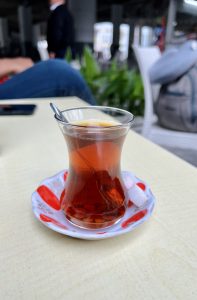 A glass of Turkish tea with sugar cubes on a saucer.

